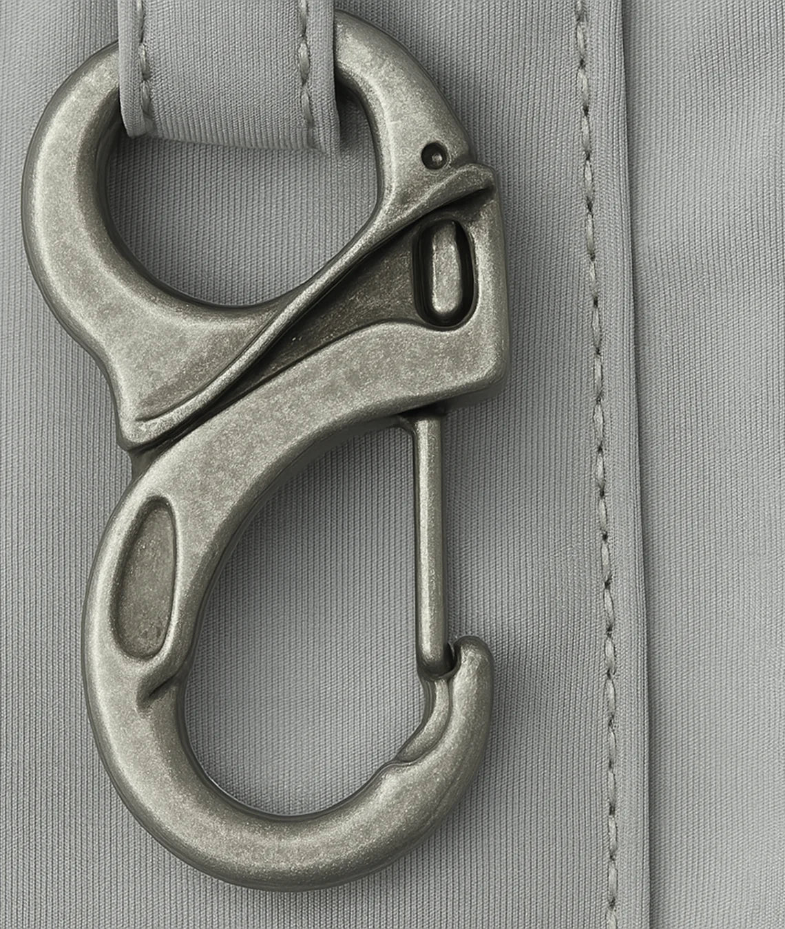 Metal carabiner attached to a gray fabric surface