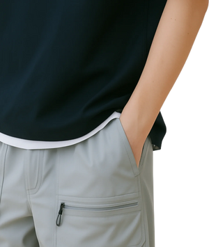 Person wearing a black sleeveless top and light gray pants with a white background