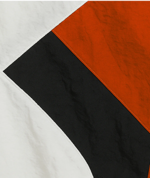Close-up of fabric with black, orange, and white sections on a white background