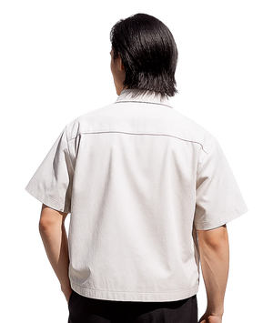 Person wearing a beige short-sleeve shirt on a white background