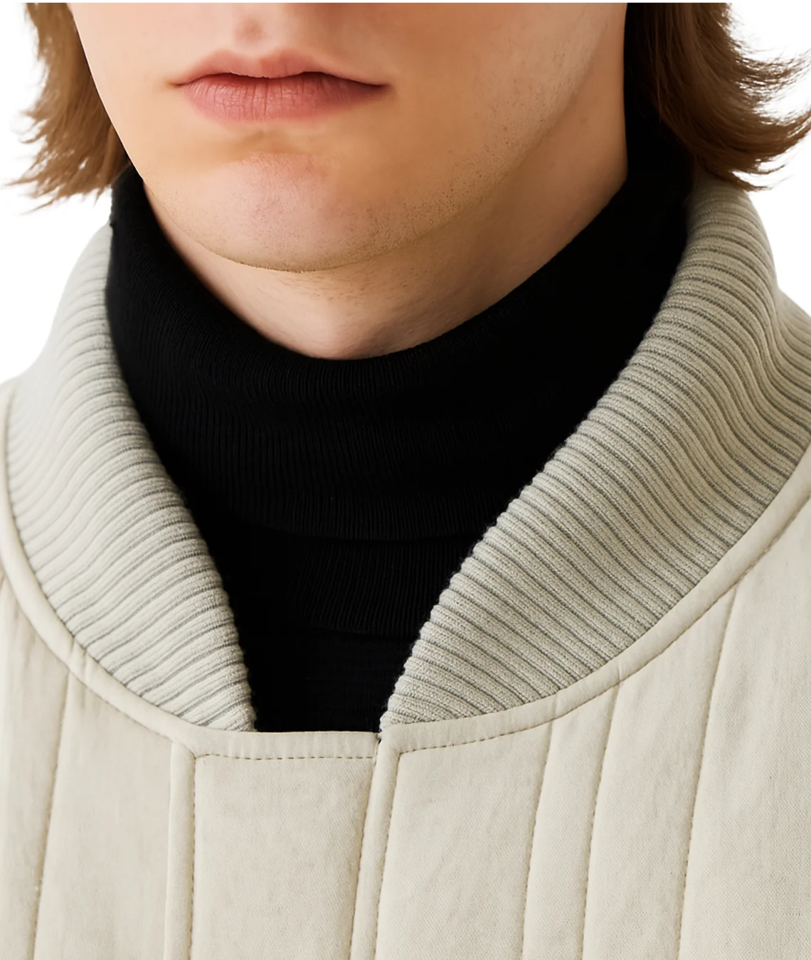Close-up of a person wearing a light gray coat with a black turtleneck sweater underneath.